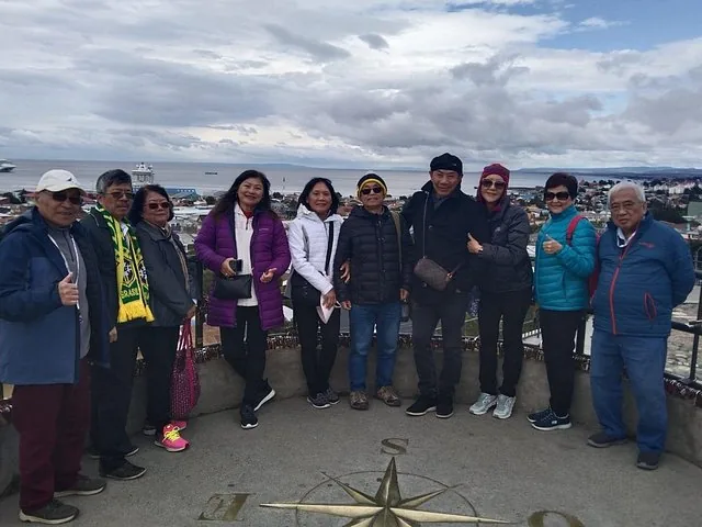 Tour group posing at a viewpoint overlooking a city and the sea