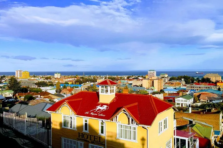 Vue urbaine avec des toits colorés, un hôtel jaune et l'océan en arrière-plan
