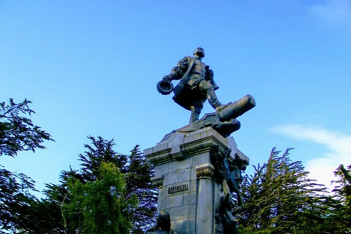 Statue en bronze d'un explorateur sur un piédestal en pierre sur fond de ciel bleu